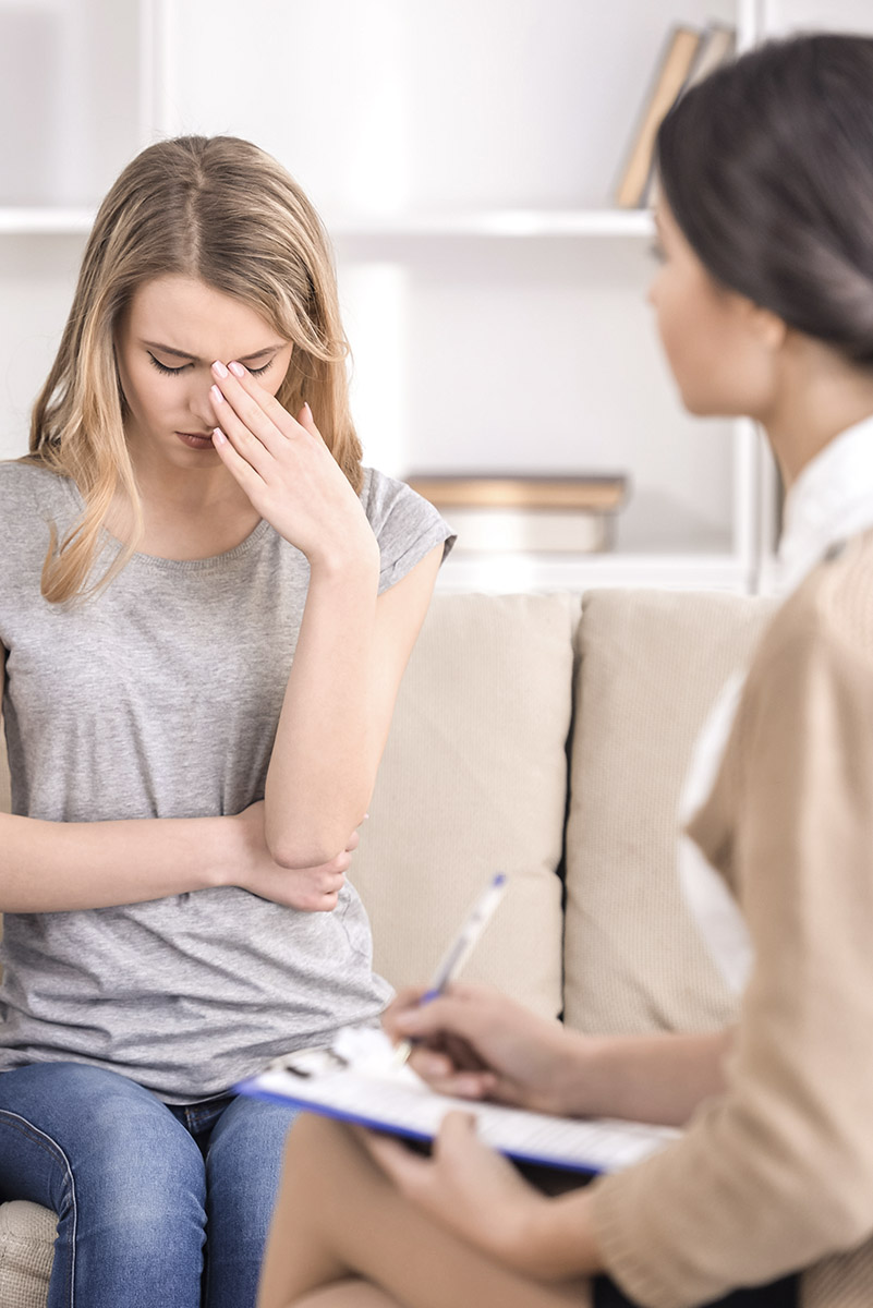 Psicología legal ayudando a una mujer joven con un problema familiar en una consulta psicológica.